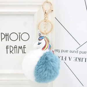 Detailed view of the blue and white faux fur unicorn pompom with golden lobster clasp