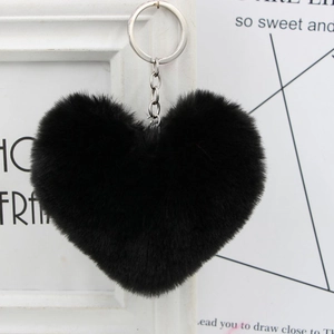 Detail of soft black heart-shaped faux fur keychain with silver metal ring on white background