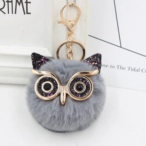 Detail of grey fluffy owl keychain with sequined ears and gold metallic eye frames