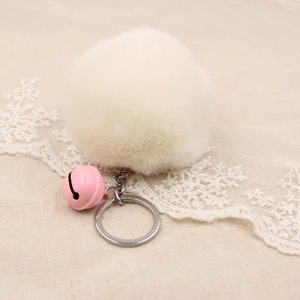 Detail of fluffy white faux fur pompom keychain with pink bell and silver metal ring