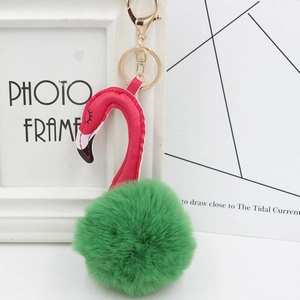 Detail of pink leather flamingo keychain with a green faux fur pompom and gold clip