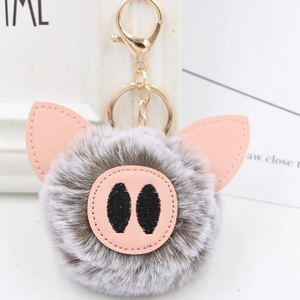 Close-up of cute plush pig keychain with soft grey fur, pink ears and golden lobster clasp