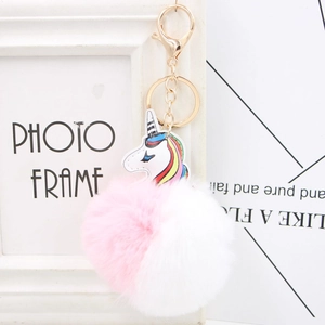 Macro detail of rainbow unicorn keychain featuring dual-tone fluffy pom pom and golden hook