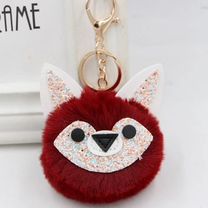 Detail showing red faux fur fox pompom keychain with golden clasp and glitter ears