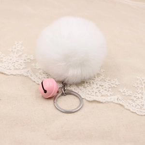 Close-up of white faux rabbit fur pom pom keychain with pink bell and silver ring