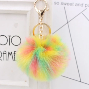 Multicolor faux fur pom pom keychain with gold clasp on a minimalist photo frame background