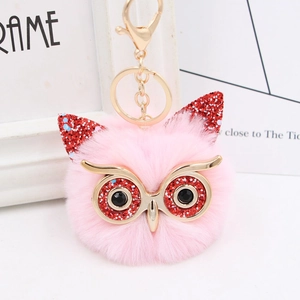 Close-up of pink faux fur owl keychain with golden sequin eyes and lobster clasp details