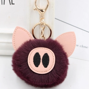 Detail of cute purple plush pig keychain with soft faux fur and golden metal lobster clasp