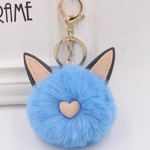 Gros plan du porte-clés en fourrure bleue avec oreilles de chat roses et fermoir doré