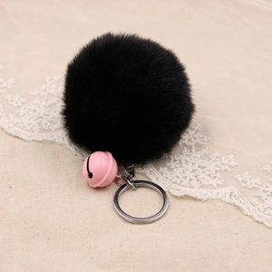 Detail of soft black faux fur pompom keychain with a cute pink bell and metal ring