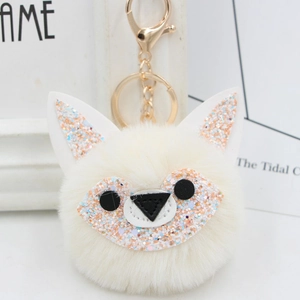 Detail of fox plush keychain with white faux fur pompom and shiny sequin accents
