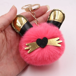 Détail du porte-clés en peluche rose vif avec oreilles de chat dorées et cœur