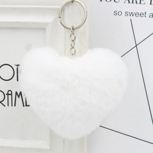 White heart-shaped faux fur keychain with silver metal ring hanging on a decorative frame