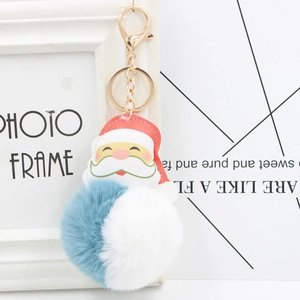 Detail showing the fluffy two-tone faux fur pompom and Santa charm on a gold keychain