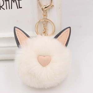 Gros plan du porte-clés pompon blanc avec oreilles de chat et détail de cœur