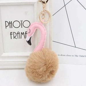 Close-up of pink flamingo plush keychain with brown fur ball and golden metal clasp