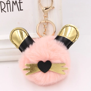 Détail d'un porte-clés en peluche rose avec oreilles de chat et fermoir doré