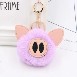 Detailed macro view of purple plush pig keychain with soft pom-pom fur and golden hardware