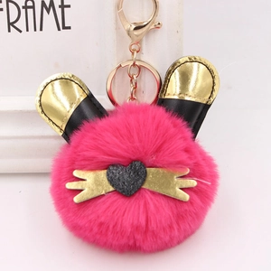 Détail du porte-clés pompon rose avec oreilles dorées et fermoir à ressort en métal