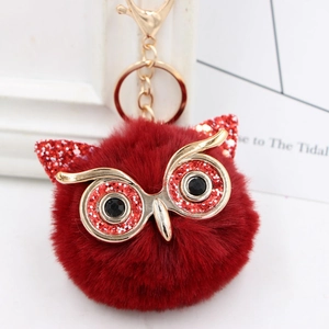 Close-up of red sequin owl plush keychain with fluffy faux fur and gold metal details