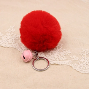 Close-up of soft red faux fur pompom keychain with a pink bell and silver metal ring