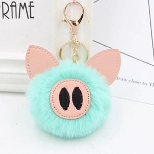 Close-up of mint green plush pig keychain with golden metal ring and lobster clasp detail