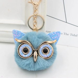 Close-up of grey plush owl keychain with sparkling sequins and gold metal ring