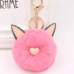 Détail d'un porte-clés en peluche rose avec oreilles de chat, cœur et métal doré