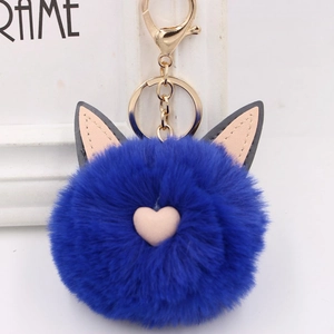 Vue détaillée du porte-clés pompon bleu roi oreilles de chat avec un petit cœur rose