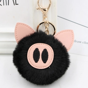 Close-up of fluffy black faux fur pig keychain with pink leather ears and gold lobster clasp