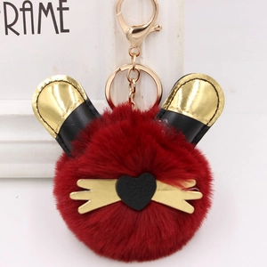 Détail d'un porte-clés chat en fausse fourrure rouge avec oreilles en cuir et fermoir doré