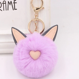 Détail d'un porte-clés pompon en fausse fourrure violette avec oreilles de chat et cœur rose