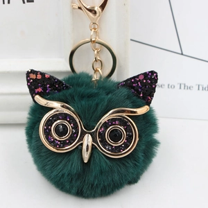 Detail of owl plush keychain featuring dark green faux fur and shiny sequins