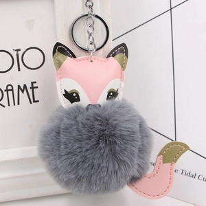 Detail of cute fox keychain with fluffy grey faux fur ball and pink leather accents
