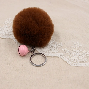Detail of dark brown faux fur pom pom keychain with pink bell and silver metal ring