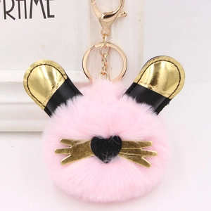 Gros plan du porte-clés chat en peluche rose avec oreilles dorées et nez en cœur