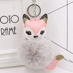 Close-up of cute fox pompom keychain with grey faux fur and pink leather details
