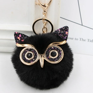 Detailed close-up of fluffy black owl keychain with sequin accents and gold metal clip