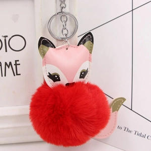 Detail view of pink faux leather fox keychain with a fluffy red pompom and silver ring