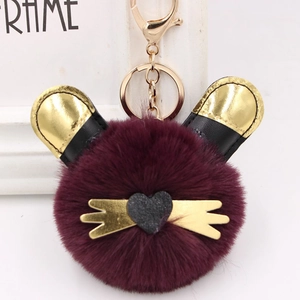 Détail du porte-clés en peluche bordeaux avec oreilles dorées et fermoir en métal doré
