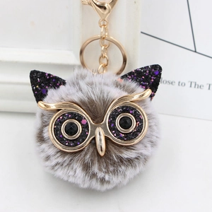 Close-up of owl keychain with grey faux fur, glitter details, and gold lobster clasp