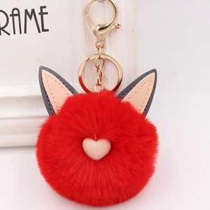 Vue détaillée d'un porte-clés en peluche rouge avec oreilles de chat et cœur doré