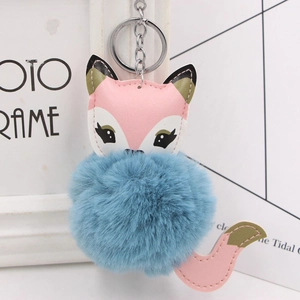 Detailed view of fox keychain with blue faux fur pompom and colorful PU leather stitching