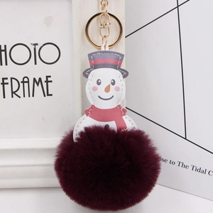 Macro detail of plush snowman keychain with burgundy faux fur ball and gold metal hardware