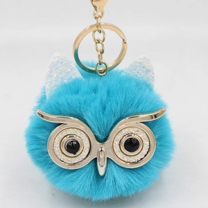 Macro view of blue plush owl keychain with gold glitter ears and metallic glasses
