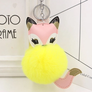 Detail of cute fox plush keychain featuring yellow fur ball and pink faux leather accents