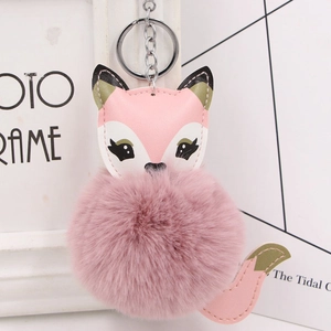 Close-up of pink fox faux fur pom-pom keychain with green leather ears and silver ring
