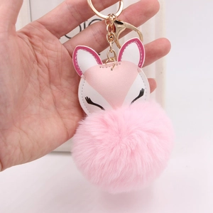 Detail of pink fox faux fur keychain with gold lobster clasp held in hand for size context