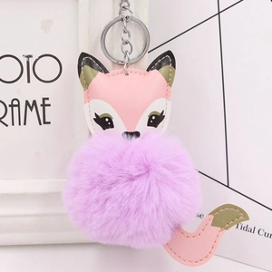 Close-up of cute fox keychain with fluffy purple faux fur ball and pink leather details