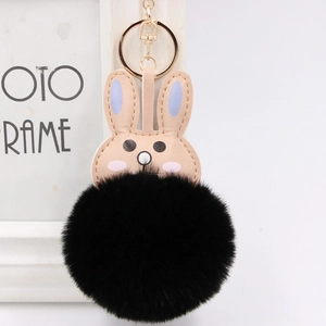 Detail of cute rabbit plush keychain with black faux fur ball and gold metal ring